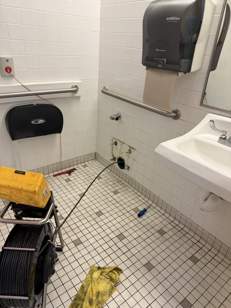 Commercial restroom drain work in progress with equipment on site