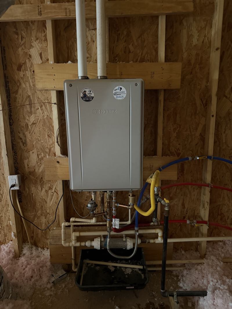Tankless water heater installed with gas and water connections in framing