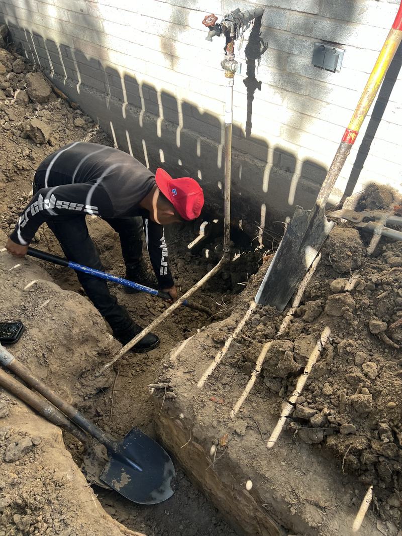 Plumber working in an excavated trench on an underground line